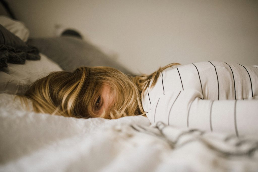 Person in bed struggling with excessive daytime sleepiness, representing idiopathic hypersomnia in Canada